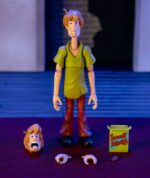 SHAGGY SCOOBY-DOO 1/12 ¡Prepárate para añadir a tu colección al ícono de los misterios y los sándwiches con la figura de acción de Scooby-Doo Shaggy a escala 1:12 de Jada Toys! Esta detallada pieza de colección captura al tranquilo pero adorable Norville "Shaggy" Rogers, el siempre hambriento mejor amigo de Scooby-Doo y miembro clave de Misterios S.A. Ya sea huyendo de fantasmas, resolviendo misterios (casi sin querer) o devorando un sándwich enorme, Shaggy siempre está listo para la aventura, ¡si no le da demasiado miedo! Diseñada por expertos a escala 1:12, esta figura luce la figura espigada de Shaggy, su característica camisa verde y sus clásicos pantalones de campana marrones. Gracias a su impresionante articulación, puedes colocarlo en diversas posturas expresivas, ya sea corriendo tras un fantasma espeluznante o sosteniendo una caja de Scooby Snacks. Este set incluye accesorios para resolver misterios, como cabezas y manos intercambiables para diferentes expresiones de terror y deleite, y una clásica caja de Scooby Snacks. Empaquetada en una caja premium inspirada en la estética clásica de Scooby-Doo, esta figura es imprescindible para los fans de la serie atemporal. Jada Toys mantiene su compromiso con la calidad y la nostalgia, asegurando que Shaggy esté listo para unirse a tu colección. ¡Solo asegúrate de tener muchos bocadillos a mano! Porque, seamos realistas... ¡siempre tiene hambre!