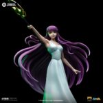 SAORI KIDO SAINT SEIYA ART SCALE 1/10. Iron Studios presenta con orgullo la estatua "Saori Kido Athena Deluxe – Saint Seiya – Art Scale 1/10", una exquisita representación de la diosa Atenea reencarnada en la icónica serie "Saint Seiya". Esta impresionante y detallada estatua pintada a mano captura a Saori Kido en toda su gracia y dignidad. De pie sobre un altar de hormigón, esta joven de figura esbelta y curva, de largo cabello morado, sostiene en el aire su bastón sagrado. Lleva un vestido largo blanco y muestra un rostro tranquilo y sereno. Debajo de sus pies, en los escalones milenarios de su santuario, se encuentran cinco Cajas de Pandora de los Santos de Bronce: Pegaso, Cisne, Dragón, Andrómeda y Fénix, que contienen las poderosas Telas. Esta pieza exclusiva de edición limitada, realizada en polystone, es una verdadera obra de arte para fanáticos y coleccionistas de "Saint Seiya".