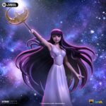 SAORI KIDO SAINT SEIYA ART SCALE 1/10. Iron Studios presenta con orgullo la estatua "Saori Kido Athena Deluxe – Saint Seiya – Art Scale 1/10", una exquisita representación de la diosa Atenea reencarnada en la icónica serie "Saint Seiya". Esta impresionante y detallada estatua pintada a mano captura a Saori Kido en toda su gracia y dignidad. De pie sobre un altar de hormigón, esta joven de figura esbelta y curva, de largo cabello morado, sostiene en el aire su bastón sagrado. Lleva un vestido largo blanco y muestra un rostro tranquilo y sereno. Debajo de sus pies, en los escalones milenarios de su santuario, se encuentran cinco Cajas de Pandora de los Santos de Bronce: Pegaso, Cisne, Dragón, Andrómeda y Fénix, que contienen las poderosas Telas. Esta pieza exclusiva de edición limitada, realizada en polystone, es una verdadera obra de arte para fanáticos y coleccionistas de "Saint Seiya".
