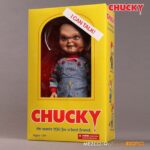 TALKING SNEERING CHUCKY CHILD’S PLAY. Mezco Toyz reincorpora a su colección MDS Mega Scale, esta figura parlante de Chucky en su versión más limpia y clásica, antes de que las cicatrices y el daño marcaran su rostro en las películas de la saga "Child’s Play" ("Muñeco diabólico" en España). Esta versión muestra a Chucky con su característico conjunto de los Good Guys, sin cortes ni desgastes, tal como sus primeras apariciones en pantalla. Mide 38 cm de alto, presenta 11 puntos de articulación, ojos con acabado vítreo realista y cabello naranja sintético. Viste ropa de tela auténtica y está equipada con un mecanismo de voz que reproduce en inglés varias frases icónicas del personaje, desde su famoso "My name is Chucky" hasta otras más siniestras.