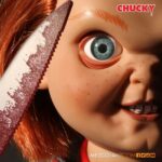 TALKING SNEERING CHUCKY CHILD’S PLAY. Mezco Toyz reincorpora a su colección MDS Mega Scale, esta figura parlante de Chucky en su versión más limpia y clásica, antes de que las cicatrices y el daño marcaran su rostro en las películas de la saga "Child’s Play" ("Muñeco diabólico" en España). Esta versión muestra a Chucky con su característico conjunto de los Good Guys, sin cortes ni desgastes, tal como sus primeras apariciones en pantalla. Mide 38 cm de alto, presenta 11 puntos de articulación, ojos con acabado vítreo realista y cabello naranja sintético. Viste ropa de tela auténtica y está equipada con un mecanismo de voz que reproduce en inglés varias frases icónicas del personaje, desde su famoso "My name is Chucky" hasta otras más siniestras.