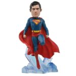 SUPERMAN 2025 DC UNIVERSE HEAD KNOCKER. Neca presenta la figura de Superman basada en el protagonista de la película homónima de 2025. Se muestra sobre una base translúcida de cristales de la Fortaleza de la Soledad, con su clásico traje azul y capa roja. Mide 21,5 cm, está fabricada con resina y pintada a mano con gran nivel de detalle. Cuenta con un mecanismo de resorte que permite el característico movimiento de cabeza de las figuras de la colección Head Knocker.