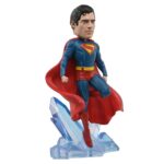 SUPERMAN 2025 DC UNIVERSE HEAD KNOCKER. Neca presenta la figura de Superman basada en el protagonista de la película homónima de 2025. Se muestra sobre una base translúcida de cristales de la Fortaleza de la Soledad, con su clásico traje azul y capa roja. Mide 21,5 cm, está fabricada con resina y pintada a mano con gran nivel de detalle. Cuenta con un mecanismo de resorte que permite el característico movimiento de cabeza de las figuras de la colección Head Knocker.
