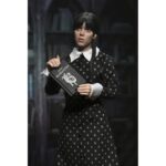 WEDNESDAY ADDAMS CLOTHED CLASSIC DRESS. Neca presenta la figura articulada de 20 cm de Wednesday Addams (conocida como Miércoles Addams en España), basada en su icónica aparición con vestido clásico en la serie de Netflix "Wednesday". La figura pertenece a la línea Clothed Action y está vestida con ropa de tela. Totalmente articulada, permite múltiples poses. Incluye 1x libro de Frankenstein, 2x set de manos intercambiables y 1x figura de Cosa.