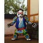 ULTIMATE PANDA KHAN TEENAGE MUTANT NINJA TURTLES CARTOON. Neca, en colaboración con Gaelstone Media, presenta la esperada figura Ultimate Panda Khan basada en la serie animada "Teenage Mutant Ninja Turtles". Esta figura mide 18 cm e incluye 2x cabezas intercambiables, 4x manos intercambiables, 1x mochila, 1x sombrero de bambú, 1x par de garras y 1x Morning Qi. Las partes superiores de las cabezas también son removibles para colocar el sombrero. Se presenta en una caja con ventana y tapa frontal abatible.