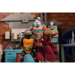 CREEPY EDDIE AND SHIBANO-SAMA TEENAGE MUTANT NINJA TURTLES CARTOON. Neca incorpora a su catálogo este set de figuras articuladas de Creepy Eddie y Shibano-Sama, basado en el cómic "Teenage Mutant Ninja Turtles: Saturday Morning Adventures". Ambas figuras tienen 18 cm de altura e incluyen 6x pares de manos intercambiables, 1x katana, 2x partes inferiores fantasmales, 1x par de tirantes removibles de Creepy Eddie, 1x casco Dream-O-Vision (compatible con la mayoría de las figuras de esta colección), y otros accesorios. El set incorpora una base de exposición con brazo articulado oficial de Neca. Presentado en una caja ilustrada con ventana.