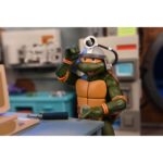 CREEPY EDDIE AND SHIBANO-SAMA TEENAGE MUTANT NINJA TURTLES CARTOON. Neca incorpora a su catálogo este set de figuras articuladas de Creepy Eddie y Shibano-Sama, basado en el cómic "Teenage Mutant Ninja Turtles: Saturday Morning Adventures". Ambas figuras tienen 18 cm de altura e incluyen 6x pares de manos intercambiables, 1x katana, 2x partes inferiores fantasmales, 1x par de tirantes removibles de Creepy Eddie, 1x casco Dream-O-Vision (compatible con la mayoría de las figuras de esta colección), y otros accesorios. El set incorpora una base de exposición con brazo articulado oficial de Neca. Presentado en una caja ilustrada con ventana.