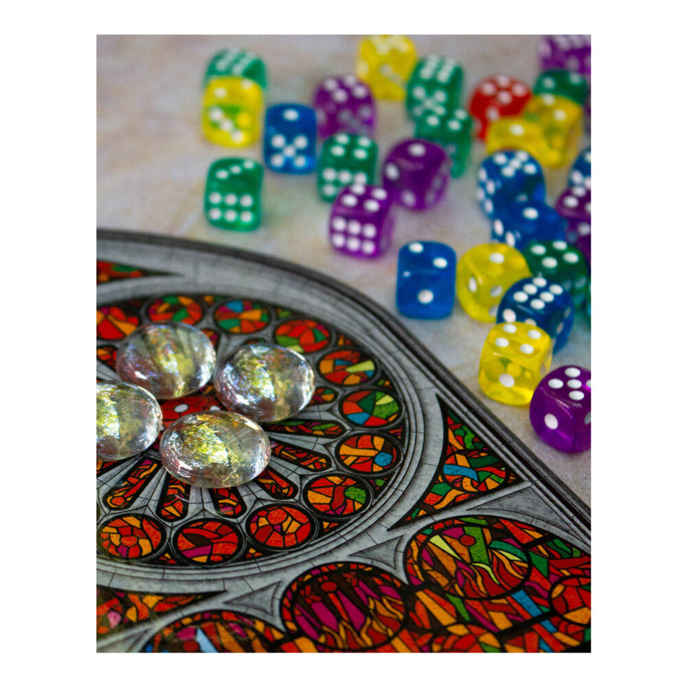 Sagrada. Es un juego de mesa abstracto, en el que los jugadores tomarán el papel de artistas creadores de vitrales que intentarán producir la pieza más hermosa para exhibirla en el templo expiatorio de la sagrada familia de antoni gaudí. Como artistas, manipularemos piezas de vidrio, que en este juego se representan con dados de diferentes colores y grados de opacidad, indicados por el valor del dado, cuanto más bajo sea su valor, menor será su opacidad.   al inicio del juego tendremos que elegir de manera aleatoria dos cartas de patrón y un tablero de marco. De las dos cartas de patrón se elige una, que se emplea durante toda la partida y se intentará completar, mientras que la otra se descarta. Este patrón marca algunas opacidades y número de dado que tendremos que conseguir. También, en la parte inferior, se indica su nivel de dificultad, que nos dará útiles fichas de donativos para poder pagar el uso de las cartas de herramienta del juego y que nos ayudarán a modificar restricciones de las reglas. Al inicio de cada partida de sagrada se colocarán los 90 dados en la bolsa, se elegirá al azar el jugador inicial, que será quien saque de la bolsa, sin mirar, una cantidad de dados igual al doble de jugadores más uno (por ejemplo, si hay 2 jugadores sacaremos 5 dados). La partida se desarrolla en el sentido de las manecillas del reloj y cada jugador puede llevar a cabo las siguientes acciones en cualquier orden: elegir un dado y colocarlo en su vitral teniendo en cuenta que debe estar adyacente a otros dados, usar una carta de herencia pagando su coste en donativos, o pasar un turno sin realizar acciones. Tras el turno del último jugador sigue la ronda, pero en sentido contrario, y los dados restantes van al marcador de ronda, hasta jugar un total de 10 rondas.. Sagrada se puede jugar en modo solitario o con hasta cuatro jugadores, en partidas que duran de 30 a 45 minutos. Es ideal para los amantes de los juegos abstractos como los sudokus o los rompecabezas, ya que intentar armar los patrones con todas las restricciones aplicadas les proporcionará muchas partidas llenas de diversión. Conviértete en un artista del vitral en sagrada, demuestra que eres quien tienes las mejores dotes artísticas y crea la mejor obra de arte para ser exhibida en el templo de la sagrada familia en este juego abstracto de colocación de dados.  consíguelo en tu tienda especializada en juegos de mesa favorita.
