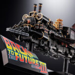 TIME TRAIN BACK TO THE FUTURE III CHOGOKIN. Presenta dentro de la línea Chogokin la máquina del tiempo con forma de locomotora de vapor que inventa el Dr. Emmett Brown en la película de 1990 "Back to the Future Part III" (o "Regreso al Futuro III" en España). Esta reproducción coleccionable que conmemora el 40º aniversario de la primera película está fabricada con ABS, PVC y metal, y tiene una longitud de 48 cm. La base que recrea una vía de tren alcanza los 56 cm de largo y está decorada con el logotipo oficial de la película. Además, cuenta con un mecanismo que gira las ruedas y eleva el vehículo. Al añadir las alas incluidas como accesorio se completa el aspecto de la máquina del tiempo en modo vuelo. Los LED bajo la locomotora y de la parte posterior se iluminan recreando el efecto de propulsión de la película. Algunas piezas se activan con electricidad como los engranajes de la locomotora que giran y cambian de dirección o la luz blanca del lateral que se enciende como en el filme. La puerta del conductor se abre hacia arriba, dejando al descubierto el interior de la cabina que se ha esculpido en base a documentación oficial. Se incluyen las figuras de los personajes que aparecen en la misma secuencia de la película y cuentan con una altura aproximada de 4 cm. La fuente de alimentación principal y el conector USB-C están situados en un extremo de la base, lo que elimina la necesidad de pilas para alimentar los diferentes mecanismos y las 56 luces LED. Se incluye un cable USB Type-A, pero no un adaptador USB. UNIDADES LIMITADAS.