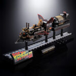 TIME TRAIN BACK TO THE FUTURE III CHOGOKIN. Presenta dentro de la línea Chogokin la máquina del tiempo con forma de locomotora de vapor que inventa el Dr. Emmett Brown en la película de 1990 "Back to the Future Part III" (o "Regreso al Futuro III" en España). Esta reproducción coleccionable que conmemora el 40º aniversario de la primera película está fabricada con ABS, PVC y metal, y tiene una longitud de 48 cm. La base que recrea una vía de tren alcanza los 56 cm de largo y está decorada con el logotipo oficial de la película. Además, cuenta con un mecanismo que gira las ruedas y eleva el vehículo. Al añadir las alas incluidas como accesorio se completa el aspecto de la máquina del tiempo en modo vuelo. Los LED bajo la locomotora y de la parte posterior se iluminan recreando el efecto de propulsión de la película. Algunas piezas se activan con electricidad como los engranajes de la locomotora que giran y cambian de dirección o la luz blanca del lateral que se enciende como en el filme. La puerta del conductor se abre hacia arriba, dejando al descubierto el interior de la cabina que se ha esculpido en base a documentación oficial. Se incluyen las figuras de los personajes que aparecen en la misma secuencia de la película y cuentan con una altura aproximada de 4 cm. La fuente de alimentación principal y el conector USB-C están situados en un extremo de la base, lo que elimina la necesidad de pilas para alimentar los diferentes mecanismos y las 56 luces LED. Se incluye un cable USB Type-A, pero no un adaptador USB. UNIDADES LIMITADAS.