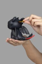 TOOTHLESS HOW TO TRAIN YOUR DRAGON PIGGY VINYL. Beast Kingdom presenta su nueva línea de huchas "Piggy Bank". Fabricada de vinilo, tamaño aprox. 12 cm. Si eres fan de Cómo Entrenar a tu Dragón, esta hucha de Desdentao de 12 cm es el complemento perfecto para tu colección. Con un diseño fiel al carismático Furia Nocturna, esta figura funciona tanto como elemento decorativo como para guardar tus ahorros de forma divertida. Fabricada en materiales resistentes y con acabados de gran calidad, la hucha presenta detalles cuidados: desde sus alas plegadas hasta su característica expresión amistosa. Ideal para niños y coleccionistas, aporta un toque de magia vikinga a cualquier habitación.