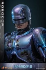 ROBOCOP 2 MOVIE MASTERPIECE HOT TOYS 1/6. Es considerada una película clásica de acción y ciencia ficción, muy querida por muchos fans. La historia sigue a RoboCop, un agente de la ley cíborg que antes era un humano llamado Alex Murphy. Tras ser brutalmente asesinado en acto de servicio, se transforma en un poderoso robot de alta tecnología con habilidades avanzadas. Posee superfuerza, visión mejorada y un compromiso inquebrantable con la ley. En "RoboCop 2", RoboCop continúa protegiendo a los ciudadanos de Detroit. Se enfrenta a una nueva amenaza cuando un ejecutivo rebelde de OCP desarrolla una versión más avanzada y malévola de RoboCop, lo que supone un grave desafío para su misión y la seguridad de la ciudad.