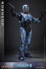 ROBOCOP 2 MOVIE MASTERPIECE HOT TOYS 1/6. Es considerada una película clásica de acción y ciencia ficción, muy querida por muchos fans. La historia sigue a RoboCop, un agente de la ley cíborg que antes era un humano llamado Alex Murphy. Tras ser brutalmente asesinado en acto de servicio, se transforma en un poderoso robot de alta tecnología con habilidades avanzadas. Posee superfuerza, visión mejorada y un compromiso inquebrantable con la ley. En "RoboCop 2", RoboCop continúa protegiendo a los ciudadanos de Detroit. Se enfrenta a una nueva amenaza cuando un ejecutivo rebelde de OCP desarrolla una versión más avanzada y malévola de RoboCop, lo que supone un grave desafío para su misión y la seguridad de la ciudad.