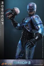 ROBOCOP 2 MOVIE MASTERPIECE HOT TOYS 1/6. Es considerada una película clásica de acción y ciencia ficción, muy querida por muchos fans. La historia sigue a RoboCop, un agente de la ley cíborg que antes era un humano llamado Alex Murphy. Tras ser brutalmente asesinado en acto de servicio, se transforma en un poderoso robot de alta tecnología con habilidades avanzadas. Posee superfuerza, visión mejorada y un compromiso inquebrantable con la ley. En "RoboCop 2", RoboCop continúa protegiendo a los ciudadanos de Detroit. Se enfrenta a una nueva amenaza cuando un ejecutivo rebelde de OCP desarrolla una versión más avanzada y malévola de RoboCop, lo que supone un grave desafío para su misión y la seguridad de la ciudad.