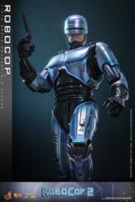 ROBOCOP 2 MOVIE MASTERPIECE HOT TOYS 1/6. Es considerada una película clásica de acción y ciencia ficción, muy querida por muchos fans. La historia sigue a RoboCop, un agente de la ley cíborg que antes era un humano llamado Alex Murphy. Tras ser brutalmente asesinado en acto de servicio, se transforma en un poderoso robot de alta tecnología con habilidades avanzadas. Posee superfuerza, visión mejorada y un compromiso inquebrantable con la ley. En "RoboCop 2", RoboCop continúa protegiendo a los ciudadanos de Detroit. Se enfrenta a una nueva amenaza cuando un ejecutivo rebelde de OCP desarrolla una versión más avanzada y malévola de RoboCop, lo que supone un grave desafío para su misión y la seguridad de la ciudad.