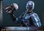 ROBOCOP 2 MOVIE MASTERPIECE HOT TOYS 1/6. Es considerada una película clásica de acción y ciencia ficción, muy querida por muchos fans. La historia sigue a RoboCop, un agente de la ley cíborg que antes era un humano llamado Alex Murphy. Tras ser brutalmente asesinado en acto de servicio, se transforma en un poderoso robot de alta tecnología con habilidades avanzadas. Posee superfuerza, visión mejorada y un compromiso inquebrantable con la ley. En "RoboCop 2", RoboCop continúa protegiendo a los ciudadanos de Detroit. Se enfrenta a una nueva amenaza cuando un ejecutivo rebelde de OCP desarrolla una versión más avanzada y malévola de RoboCop, lo que supone un grave desafío para su misión y la seguridad de la ciudad.