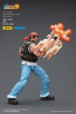 RALF JONES THE KING OF FIGHTERS’98 HERO TEAM. JoyToy x SNK presentan la figura de acción de Ralf Jones de la serie «The King of Fighters '98», tamaño aprox. 12 cm. Esta figura de acción a escala 1/12 presenta el robusto diseño militar, la musculatura y el característico pañuelo rojo de Ralf. Con una articulación dinámica y accesorios detallados para las armas, esta figura es perfecta para los fans que quieren exhibir todo su poder.