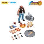 RALF JONES THE KING OF FIGHTERS’98 HERO TEAM. JoyToy x SNK presentan la figura de acción de Ralf Jones de la serie «The King of Fighters '98», tamaño aprox. 12 cm. Esta figura de acción a escala 1/12 presenta el robusto diseño militar, la musculatura y el característico pañuelo rojo de Ralf. Con una articulación dinámica y accesorios detallados para las armas, esta figura es perfecta para los fans que quieren exhibir todo su poder.