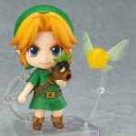 LINK THE LEGEND OF ZELDA MAJORA’S MASK NENDOROID. Good Smile Company vuelve a introducir en su colección Nendoroid la figura articulada de Link basada en el protagonista del videojuego "The Legend of Zelda: Majora's Mask 3D" para Nintendo 3DS. Esta edición cuenta con una selección de accesorios mayor de lo habitual: 2x placas faciales intercambiables (sonriente y gritando), 1x escudo del Héroe, 1x espada Kokiri, 1x poción de salud, 1x capucha de conejo, 1x Máscara Deku, 1x Máscara Goron, 1x Máscara Zora, 1x Máscara de Majora y 1x hada Tatl con soporte. Mide aproximadamente 10 cm de altura y está fabricada en PVC y ABS. Se presenta en caja con ventana y cuenta con una base cuadrada transparente con soporte articulado para exposición.