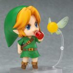 LINK THE LEGEND OF ZELDA MAJORA’S MASK NENDOROID. Good Smile Company vuelve a introducir en su colección Nendoroid la figura articulada de Link basada en el protagonista del videojuego "The Legend of Zelda: Majora's Mask 3D" para Nintendo 3DS. Esta edición cuenta con una selección de accesorios mayor de lo habitual: 2x placas faciales intercambiables (sonriente y gritando), 1x escudo del Héroe, 1x espada Kokiri, 1x poción de salud, 1x capucha de conejo, 1x Máscara Deku, 1x Máscara Goron, 1x Máscara Zora, 1x Máscara de Majora y 1x hada Tatl con soporte. Mide aproximadamente 10 cm de altura y está fabricada en PVC y ABS. Se presenta en caja con ventana y cuenta con una base cuadrada transparente con soporte articulado para exposición.