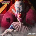 SLIM PELUCHE KILLER CLOWNS FROM OUTER SPACE MDS ROTO PLUSH. Mezco Toyz presenta dentro de su colección MDS Roto Plush este muñeco de peluche de Slim, el payaso extraterrestre experto en diversión mortal de la película de culto "Killer Klowns from Outer Space" ("Los payasos asesinos del espacio exterior" en España). Mide aproximadamente 46 cm de altura y reproduce sus rasgos caricaturescos con un acabado siniestro. Usa un traje de color rosa intenso con detalles bordados de luna creciente, cabeza esculpida con facciones exageradas y cabello naranja encendido. Cuenta con su nariz roja abultada y su perturbadora sonrisa. Se presenta en una caja con ventana troquelada perfecta para exhibición.