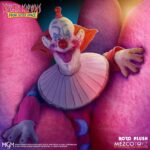 SLIM PELUCHE KILLER CLOWNS FROM OUTER SPACE MDS ROTO PLUSH. Mezco Toyz presenta dentro de su colección MDS Roto Plush este muñeco de peluche de Slim, el payaso extraterrestre experto en diversión mortal de la película de culto "Killer Klowns from Outer Space" ("Los payasos asesinos del espacio exterior" en España). Mide aproximadamente 46 cm de altura y reproduce sus rasgos caricaturescos con un acabado siniestro. Usa un traje de color rosa intenso con detalles bordados de luna creciente, cabeza esculpida con facciones exageradas y cabello naranja encendido. Cuenta con su nariz roja abultada y su perturbadora sonrisa. Se presenta en una caja con ventana troquelada perfecta para exhibición.