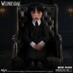 WEDNESDAY MDS ROTO PLUSH. Mezco suma a su línea MDS Roto Plush la figura de Wednesday Addams (conocida como Miércoles Addams en España), inspirada en la exitosa serie de Netflix "Wednesday". Tiene una altura aproximada de 45 cm. Se muestra con su característico gesto serio, un vestido negro manga larga con cuello alto, sus clásicas trenzas de cabello negro implantadas y zapatos al estilo Mary Jane. Cuenta con partes esculpidas sobre un cuerpo de felpa. Se presenta en una caja con ventana