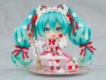 HATSUNE MIKU 15TH ANNIVERSARY NENDOROID. Good Smile suma a su catálogo Nendoroid la figura articulada de la cantante virtual de Vocaloid "Hatsune Miku" basada en la ilustración de En Morikura para conmemorar el 15º aniversario de personaje donde lleva un atuendo basado en una tarta de fresa. Cuenta con 3x placas faciales (estándar, sonriente y satisfecha), 1x tenedor, 1x macaron y 1x base con forma de plato conmemorativo. Mide aproximadamente 10 cm de altura e incluye base con soporte transparente para su exposición.