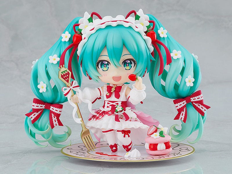 Hatsune miku 15th anniversary nendoroid. Good smile suma a su catálogo nendoroid la figura articulada de la cantante virtual de vocaloid "hatsune miku" basada en la ilustración de en morikura para conmemorar el 15º aniversario de personaje donde lleva un atuendo basado en una tarta de fresa. Cuenta con 3x placas faciales (estándar, sonriente y satisfecha), 1x tenedor, 1x macaron y 1x base con forma de plato conmemorativo. Mide aproximadamente 10 cm de altura e incluye base con soporte transparente para su exposición.