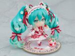 HATSUNE MIKU 15TH ANNIVERSARY NENDOROID. Good Smile suma a su catálogo Nendoroid la figura articulada de la cantante virtual de Vocaloid "Hatsune Miku" basada en la ilustración de En Morikura para conmemorar el 15º aniversario de personaje donde lleva un atuendo basado en una tarta de fresa. Cuenta con 3x placas faciales (estándar, sonriente y satisfecha), 1x tenedor, 1x macaron y 1x base con forma de plato conmemorativo. Mide aproximadamente 10 cm de altura e incluye base con soporte transparente para su exposición.