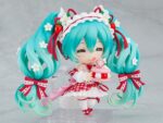HATSUNE MIKU 15TH ANNIVERSARY NENDOROID. Good Smile suma a su catálogo Nendoroid la figura articulada de la cantante virtual de Vocaloid "Hatsune Miku" basada en la ilustración de En Morikura para conmemorar el 15º aniversario de personaje donde lleva un atuendo basado en una tarta de fresa. Cuenta con 3x placas faciales (estándar, sonriente y satisfecha), 1x tenedor, 1x macaron y 1x base con forma de plato conmemorativo. Mide aproximadamente 10 cm de altura e incluye base con soporte transparente para su exposición.