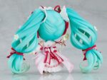 HATSUNE MIKU 15TH ANNIVERSARY NENDOROID. Good Smile suma a su catálogo Nendoroid la figura articulada de la cantante virtual de Vocaloid "Hatsune Miku" basada en la ilustración de En Morikura para conmemorar el 15º aniversario de personaje donde lleva un atuendo basado en una tarta de fresa. Cuenta con 3x placas faciales (estándar, sonriente y satisfecha), 1x tenedor, 1x macaron y 1x base con forma de plato conmemorativo. Mide aproximadamente 10 cm de altura e incluye base con soporte transparente para su exposición.