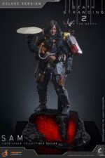 SAM (DELUXE VERSION) DEATH STRANDING 2: ON THE BEACH VIDEOGAME MASTERPIECE HOT TOYS 1/6. En Death Stranding 2: On the Beach, Sam Porter Bridges atraviesa la Australia postapocalíptica, reconstruyendo la Red Quiral y reconectando comunidades en medio de nuevas y duras amenazas. Hot Toys presenta con orgullo la figura coleccionable de Sam a escala 1/6 (versión Deluxe): una versión mejorada con numerosos accesorios y opciones de exhibición mejoradas. Al igual que la versión normal, esta figura de acción incluye una cabeza esculpida con ojos giratorios y cabello castaño oscuro cuidadosamente elaborado, un traje de puente levadizo con efecto reflectante luminiscente UV, un arnés utilitario de cuerpo entero, un esqueleto de batalla desmontable, armadura de espalda con escáner Odradek y botas de transporte, todo ello con un realismo desgastado. La versión Deluxe incluye un Bumerán de Sangre extra abierto, en homenaje al uso de la sangre de Sam en el juego. Incluye dos Pizzas de Goma, que hacen referencia a las técnicas favoritas de los fans de Pizza-Do. Además de las cargas medianas y grandes predeterminadas, también incluye un contenedor de carga extra dañado para más opciones de exhibición. La base de la figura del diorama APAS 4000 con iluminación LED completa el conjunto, permitiendo a los coleccionistas realzar su exhibición y recrear el enfrentamiento de Death Stranding 2.
