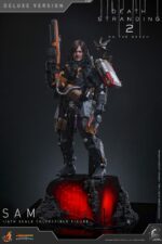 SAM (DELUXE VERSION) DEATH STRANDING 2: ON THE BEACH VIDEOGAME MASTERPIECE HOT TOYS 1/6. En Death Stranding 2: On the Beach, Sam Porter Bridges atraviesa la Australia postapocalíptica, reconstruyendo la Red Quiral y reconectando comunidades en medio de nuevas y duras amenazas. Hot Toys presenta con orgullo la figura coleccionable de Sam a escala 1/6 (versión Deluxe): una versión mejorada con numerosos accesorios y opciones de exhibición mejoradas. Al igual que la versión normal, esta figura de acción incluye una cabeza esculpida con ojos giratorios y cabello castaño oscuro cuidadosamente elaborado, un traje de puente levadizo con efecto reflectante luminiscente UV, un arnés utilitario de cuerpo entero, un esqueleto de batalla desmontable, armadura de espalda con escáner Odradek y botas de transporte, todo ello con un realismo desgastado. La versión Deluxe incluye un Bumerán de Sangre extra abierto, en homenaje al uso de la sangre de Sam en el juego. Incluye dos Pizzas de Goma, que hacen referencia a las técnicas favoritas de los fans de Pizza-Do. Además de las cargas medianas y grandes predeterminadas, también incluye un contenedor de carga extra dañado para más opciones de exhibición. La base de la figura del diorama APAS 4000 con iluminación LED completa el conjunto, permitiendo a los coleccionistas realzar su exhibición y recrear el enfrentamiento de Death Stranding 2.