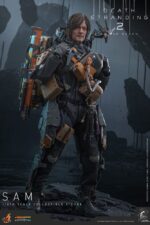 SAM DEATH STRANDING 2: ON THE BEACH VIDEOGAME MASTERPIECE HOT TOYS 1/6. En Death Stranding 2: On the Beach, el protagonista Sam Porter Bridges se embarca en una misión a través de la Australia postapocalíptica, trabajando para reconectar comunidades aisladas a través de la red Chiral en medio de nuevas amenazas ambientales y desafíos de combate. Hot Toys se complace en anunciar la figura coleccionable de Sam a escala 1/6, que captura fielmente la apariencia de Reedus en el juego. La figura de acción presenta una cabeza recién esculpida con ojos giratorios separados y un cabello castaño oscuro finamente detallado. Su traje de puente levadizo incorpora un efecto reflectante luminoso UV, complementado con un arnés utilitario de cuerpo completo, un esqueleto de batalla desmontable, armadura de espalda con escáner Odradek y botas de transporte, todo ello desgastado para un realismo auténtico y desgastado. Equipado con nueve manos enguantadas, Sam está listo para cualquier exhibición. Su arsenal incluye un Strand, una pistola ametralladora, un rifle de asalto LW Lv2 y un bumerán de sangre plegado que se puede acoplar a su arnés.