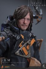 SAM DEATH STRANDING 2: ON THE BEACH VIDEOGAME MASTERPIECE HOT TOYS 1/6. En Death Stranding 2: On the Beach, el protagonista Sam Porter Bridges se embarca en una misión a través de la Australia postapocalíptica, trabajando para reconectar comunidades aisladas a través de la red Chiral en medio de nuevas amenazas ambientales y desafíos de combate. Hot Toys se complace en anunciar la figura coleccionable de Sam a escala 1/6, que captura fielmente la apariencia de Reedus en el juego. La figura de acción presenta una cabeza recién esculpida con ojos giratorios separados y un cabello castaño oscuro finamente detallado. Su traje de puente levadizo incorpora un efecto reflectante luminoso UV, complementado con un arnés utilitario de cuerpo completo, un esqueleto de batalla desmontable, armadura de espalda con escáner Odradek y botas de transporte, todo ello desgastado para un realismo auténtico y desgastado. Equipado con nueve manos enguantadas, Sam está listo para cualquier exhibición. Su arsenal incluye un Strand, una pistola ametralladora, un rifle de asalto LW Lv2 y un bumerán de sangre plegado que se puede acoplar a su arnés.