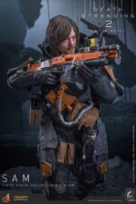 SAM DEATH STRANDING 2: ON THE BEACH VIDEOGAME MASTERPIECE HOT TOYS 1/6. En Death Stranding 2: On the Beach, el protagonista Sam Porter Bridges se embarca en una misión a través de la Australia postapocalíptica, trabajando para reconectar comunidades aisladas a través de la red Chiral en medio de nuevas amenazas ambientales y desafíos de combate. Hot Toys se complace en anunciar la figura coleccionable de Sam a escala 1/6, que captura fielmente la apariencia de Reedus en el juego. La figura de acción presenta una cabeza recién esculpida con ojos giratorios separados y un cabello castaño oscuro finamente detallado. Su traje de puente levadizo incorpora un efecto reflectante luminoso UV, complementado con un arnés utilitario de cuerpo completo, un esqueleto de batalla desmontable, armadura de espalda con escáner Odradek y botas de transporte, todo ello desgastado para un realismo auténtico y desgastado. Equipado con nueve manos enguantadas, Sam está listo para cualquier exhibición. Su arsenal incluye un Strand, una pistola ametralladora, un rifle de asalto LW Lv2 y un bumerán de sangre plegado que se puede acoplar a su arnés.