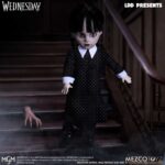 WEDNESDAY LIVING DEAD DOLLS MEZCO. Mezco Toyz vuelve a presentar dentro de su línea Living Dead Dolls la muñeca de Wednesday Addams, inspirada en la serie de Netflix "Wednesday" ("Miércoles" en España). La figura mide aproximadamente 25 cm de altura, cuenta con 5 puntos de articulación y se muestra con su característico vestido negro con cuello, mallas oscuras y botas. Luce su peinado clásico con coletas y un nuevo esculpido facial. Como accesorio se incluye su inseparable mano sirviente Cosa en pose estática. Se presenta en una caja con ventana.