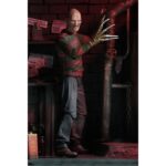 ULTIMATE FREDDY KRUEGER A NIGHTMORE ON ELM STREET PART 2. Neca vuelve a añadir a su línea Ultimate la figura de Freddy Krueger basada en la película "A Nightmare on Elm Street Part 2: Freddy's Revenge" ("Pesadilla en Elm Street 2: La venganza de Freddy" en España). Mide 18 cm e incluye 3x cabezas intercambiables, 2x perros demoníacos, 1x mano enguantada, 1x mano afilada, 1x sombrero extraíble y 1x efecto de fuego magnético. Se presenta en una caja con ventana y solapa frontal.