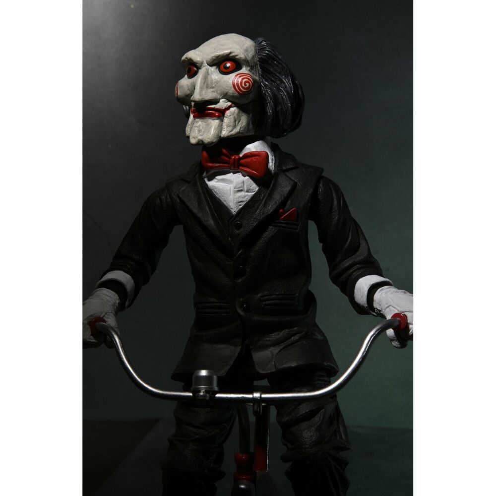 Billy the puppet on tricycle saw 12″. Neca reincorpora en su catálogo esta figura de 30 cm de billy the puppet, el siniestro muñeco de la saga "saw". Se muestra montado en su icónico triciclo rojo con zapatos de purpurina e incluye función de sonido con frases de la película. Emplea 3 baterías de 1. 5v lr44 (incluidas). Se presenta en una caja con ventana.