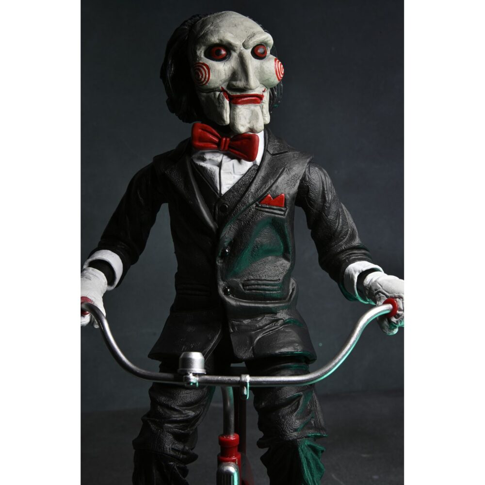 Billy the puppet on tricycle saw 12″. Neca reincorpora en su catálogo esta figura de 30 cm de billy the puppet, el siniestro muñeco de la saga "saw". Se muestra montado en su icónico triciclo rojo con zapatos de purpurina e incluye función de sonido con frases de la película. Emplea 3 baterías de 1. 5v lr44 (incluidas). Se presenta en una caja con ventana.