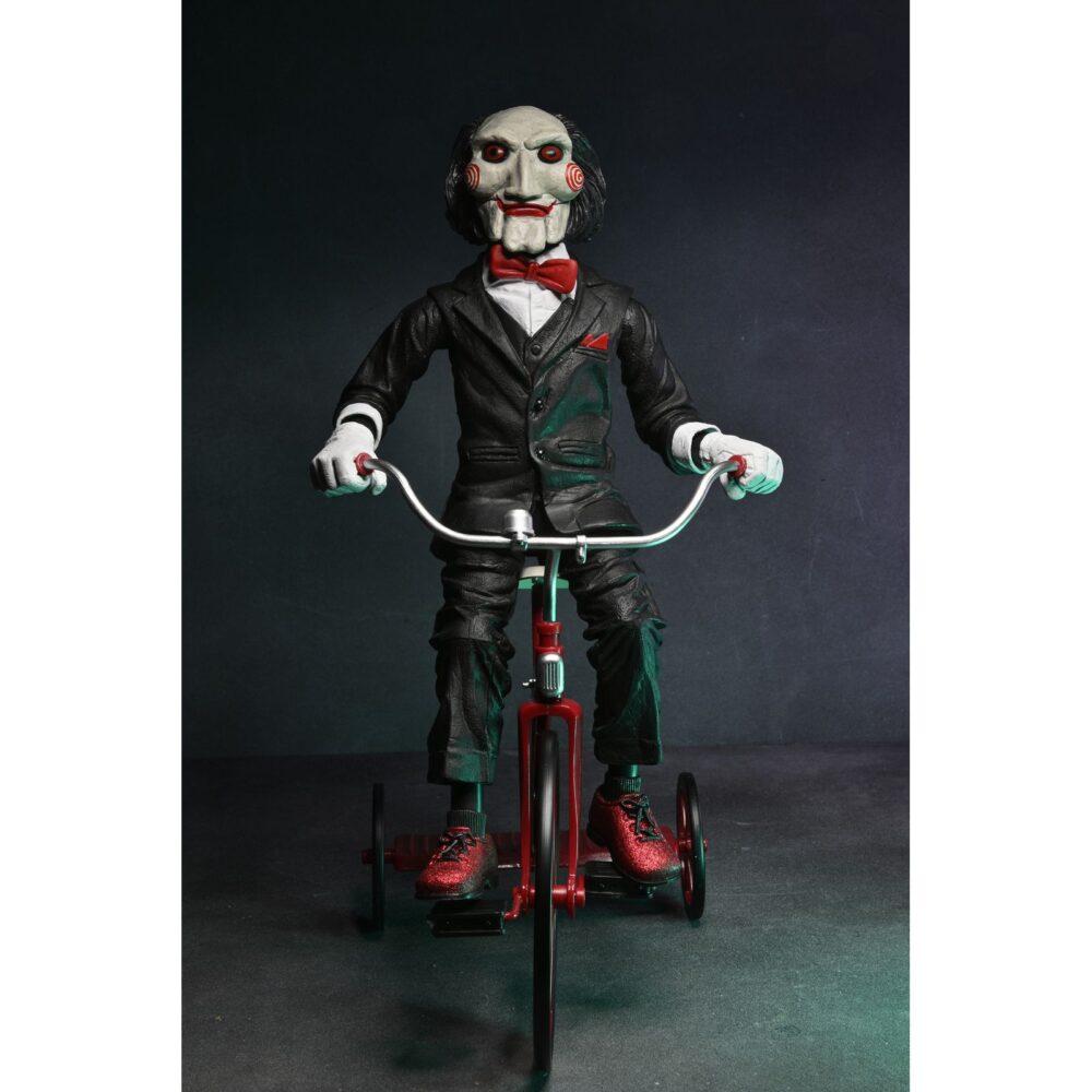 Billy the puppet on tricycle saw 12″. Neca reincorpora en su catálogo esta figura de 30 cm de billy the puppet, el siniestro muñeco de la saga "saw". Se muestra montado en su icónico triciclo rojo con zapatos de purpurina e incluye función de sonido con frases de la película. Emplea 3 baterías de 1. 5v lr44 (incluidas). Se presenta en una caja con ventana.