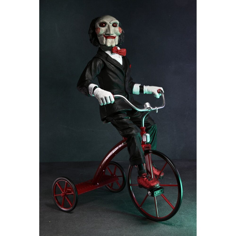 Billy the puppet on tricycle saw 12″. Neca reincorpora en su catálogo esta figura de 30 cm de billy the puppet, el siniestro muñeco de la saga "saw". Se muestra montado en su icónico triciclo rojo con zapatos de purpurina e incluye función de sonido con frases de la película. Emplea 3 baterías de 1. 5v lr44 (incluidas). Se presenta en una caja con ventana.