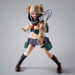 HIMIKO TOGA MY HERO ACADEMIA SH FIGUARTS. En el mundo de My Hero Academia, Himiko Toga es uno de los miembros más llamativos de la Liga de Villanos. Bajo su apariencia de colegiala se esconde una personalidad inestable y peligrosa, lo que la hace tan impredecible como formidable. Su peculiaridad, que le permite transformarse en cualquier persona cuya sangre haya ingerido, la sitúa en el centro de muchas batallas clave. Himiko encarna a una antagonista inquietante: una mezcla de fascinación mórbida y energía despreocupada, expresada a través de cambios emocionales extremos. A menudo alegre y sonriente, puede pasar instantáneamente a una locura inquietante. Esta dualidad la hace cautivadora y aterradora a la vez. La figura la muestra con su uniforme escolar, con su característico jersey beige, falda azul marino y calcetines negros largos. Su cabello rubio recogido en dos moños desordenados, su mirada traviesa y sus expresiones faciales alternativas dan vida al personaje. Los accesorios incluidos son su equipo de combate y varias manos intercambiables, lo que te permite recrear sus escenas más emblemáticas. Con una altura de unos 13 cm, esta figura articulada de S.H.Figuarts ofrece una amplia gama de opciones de posado. Las caras adicionales, las armas en miniatura y las piezas de efectos añaden una gran variedad a la exposición. Cada articulación está diseñada para posados dinámicos, lo que la convierte en una pieza perfecta para los fans que quieran revivir sus momentos más memorables de la serie.