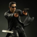 NEO THE MATRIX ART SCALE 1/10. Directamente desde una escena icónica de Matrix, Neo se lanza al aire, con su gabardina ondeando y las armas desenfundadas, desafiando la gravedad y enfrentándose a lo imposible. Esta figura lo captura en pleno salto, congelado en el momento en que las balas vuelan y el tiempo se ralentiza. Es la esencia de Matrix en una sola pose. Como héroe legendario de la trilogía, Neo simboliza la rebelión, la duda y, finalmente, la fe absoluta. Esta escultura lo captura en un momento decisivo: concentrado, en el aire y con el control absoluto. Su gabardina ondeando, sus gafas oscuras y su expresión estoica son un guiño al lenguaje visual que lo convirtió en un icono cinematográfico. La base representa una pared derruida en medio de un tiroteo: agujeros de bala, fragmentos de yeso y cables rotos. Los efectos de polvo esculpidos añaden movimiento dinámico a la escena. El marcado contraste entre su traje negro y los escombros de hormigón realza el dramatismo de la figura. Fabricada en resina y con una altura aproximada de 25 cm a escala 1/10, esta pieza forma parte de la línea Art Scale de Iron Studios, conocida por sus poses cinematográficas y sus detalles realistas. Imprescindible para los fans de Matrix y los coleccionistas de cultura pop que buscan impacto visual.
