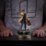 MIKEY WALSH (40TH ANNIVERSARY) THE GOONIES ART SCALE 1/10. Mikey Walsh regresa en esta figura conmemorativa del 40 aniversario de Los Goonies, capturando la energía y la determinación del valiente joven líder. De pie sobre una base con forma de cueva pirata, con un mapa del tesoro en una mano y una moneda de oro en la otra, encarna a la perfección el espíritu de la aventura infantil: misterio, valentía e imaginación. Como líder natural de la pandilla, Mikey puede que no tenga poderes ni equipo, pero lidera con esperanza y lealtad. Su pose, con la mirada puesta en el futuro, refleja ese momento icónico en el que la historia se hace realidad y los niños se convierten en héroes. La moneda que sostiene en la mano conecta el mito con la acción, la esperanza con el descubrimiento. La escultura recrea fielmente su icónico aspecto: impermeable amarillo brillante, camisa vaquera, pantalones vaqueros y zapatillas gastadas. La base está ricamente detallada, con texturas de roca, monedas de oro, reliquias antiguas y una calavera tallada, lo que evoca instantáneamente la atmósfera de la búsqueda subterránea de la película. Fabricada en resina a escala 1/10, la estatua mide aproximadamente 21 cm de altura. Forma parte de la colección Art Scale de Iron Studios, que se centra en la nostalgia y los detalles. Una pieza central perfecta para los fans de Los Goonies, o para cualquiera que todavía crea en los tesoros enterrados y las aventuras con los mejores amigos.