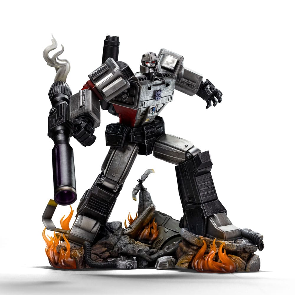 MEGATRON TRANSFORMERS DEMI ART SCALE 1/10. Encarnación de la estrategia despiadada y el poder bruto, Megatron se yergue imponente en esta pose dominante sobre los restos humeantes de sus enemigos. Inspirada en el universo clásico de Transformers, esta figura de resina captura el frío dominio y la presencia icónica del líder Decepticon. Con el cañón de fusión apuntando y listo, la mirada de Megatron se fija en su objetivo con una confianza inquebrantable. Su diseño retrofuturista —chapa metálica cepillada, estructura angular, detalles tecnológicos desgastados— se recrea con una precisión sorprendente. La base representa un campo de batalla en llamas: robots destrozados, cables rotos, llamas esculpidas y efectos de humo realzan la intensidad de la escena. El cañón brillante y aún humeante añade una dramática sensación de acción reciente. Fabricada en resina y con una altura aproximada de 32 cm a escala 1/20, esta estatua pertenece a la línea Demi Art Scale de Iron Studios. Ofrece texturas nítidas, una pose audaz y una base narrativa que realza toda la pieza. Una representación feroz e inolvidable de Megatron, perfecta para los fans que quieren que su exposición irradie amenaza.