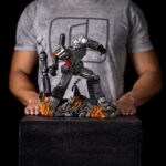 MEGATRON TRANSFORMERS DEMI ART SCALE 1/10. Encarnación de la estrategia despiadada y el poder bruto, Megatron se yergue imponente en esta pose dominante sobre los restos humeantes de sus enemigos. Inspirada en el universo clásico de Transformers, esta figura de resina captura el frío dominio y la presencia icónica del líder Decepticon. Con el cañón de fusión apuntando y listo, la mirada de Megatron se fija en su objetivo con una confianza inquebrantable. Su diseño retrofuturista —chapa metálica cepillada, estructura angular, detalles tecnológicos desgastados— se recrea con una precisión sorprendente. La base representa un campo de batalla en llamas: robots destrozados, cables rotos, llamas esculpidas y efectos de humo realzan la intensidad de la escena. El cañón brillante y aún humeante añade una dramática sensación de acción reciente. Fabricada en resina y con una altura aproximada de 32 cm a escala 1/20, esta estatua pertenece a la línea Demi Art Scale de Iron Studios. Ofrece texturas nítidas, una pose audaz y una base narrativa que realza toda la pieza. Una representación feroz e inolvidable de Megatron, perfecta para los fans que quieren que su exposición irradie amenaza.