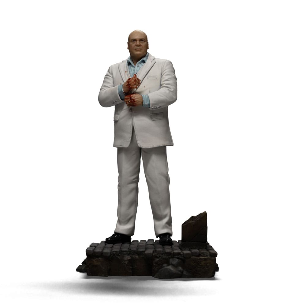 KINGPIN DAREDEVIL: BORN AGAIN ART SCALE 1/10. En el oscuro y urbano universo de Marvel, Wilson Fisk, alias Kingpin, reina sobre el crimen organizado con una inteligencia fría y mano de hierro. Enemigo emblemático de Daredevil, encarna la corrupción arraigada en las calles de Hell's Kitchen, utilizando su influencia política y su fuerza bruta para afianzar su poder. Aquí representado de pie en una postura imponente, Kingpin sujeta su bastón con calma y seguridad. Su mirada dura y su estatura imponente transmiten una autoridad indiscutible. Su atuendo, un traje blanco perfectamente cortado, contrasta con la atmósfera amenazante que lo rodea, lo que subraya su gusto por el control y la puesta en escena. Cada detalle visual está cuidadosamente trabajado: cabeza rapada, rasgos cerrados, camisa azul pálida y bastón esculpido. La base imita un adoquín urbano roto, acentuando el contraste entre su aparente elegancia y la brutalidad de su entorno. El realismo de los pliegues de la tela y la textura de la base aportan profundidad y presencia a esta pieza. Fabricada en resina, esta figura mide aproximadamente 21 cm y está diseñada a escala 1/10. Forma parte de la colección Art Scale de Iron Studios y se apoya en una base detallada, lista para completar una escena realista de Marvel o para presidir por sí sola como representación de uno de los antagonistas más poderosos del universo.