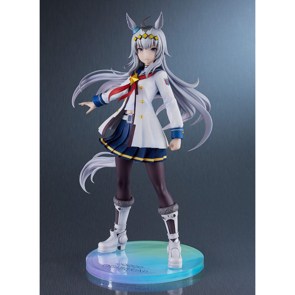OGURI CAP UMA MUSUME PRETTY DERBY ESTATUA PVC 1/7. En el mundo de Uma Musume Pretty Derby, Oguri Cap es una de las competidoras más emblemáticas, inspirada en un legendario caballo de carreras real. Tanto en el juego como en la franquicia, encarna la determinación y la elegancia, con una presencia imponente que deja huella tanto en sus rivales como en sus fans. Su papel destaca como una luchadora orgullosa y segura de sí misma, siempre dispuesta a afrontar retos en la pista de carreras. Fiel a su modelo histórico, Oguri Cap se distingue por su aplomo inquebrantable y un temperamento que inspira respeto y admiración. Esta figura captura su carisma: Oguri Cap aparece con un uniforme blanco con detalles azules y dorados, complementado con un pañuelo rojo que fluye ligeramente hacia un lado. Su larga melena plateada, adornada con una diadema con motivos de estrellas y sus orejas de caballo, cae suavemente por su espalda. La falda plisada oscura, las medias y las botas blancas enfatizan su estilo atlético y elegante. Con el puño cerrado y la mirada decidida, su pose refleja perfectamente su espíritu luchador. Fabricada en PVC a escala 1/7, la figura mide unos 25 centímetros de altura. Se pueden apreciar los finos detalles en los pliegues de su traje, los mechones de su cabello y los toques metálicos de sus accesorios. La base circular con degradados azules y morados realza su presencia dinámica y resalta su imponente silueta.
